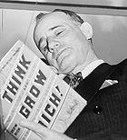 Napoleon Hill holding his book Think and Grow Rich