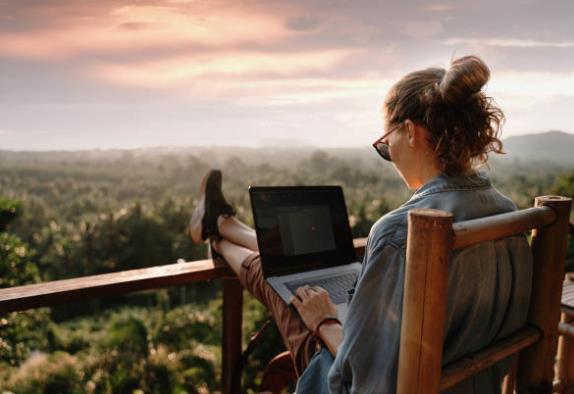 Women sitting down with her laptop enjoying the freedom and flexibility of affiliate marketing while outside in the sunshine and forests
